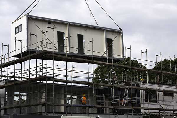Modular component being lifted onto a house by a crane.
