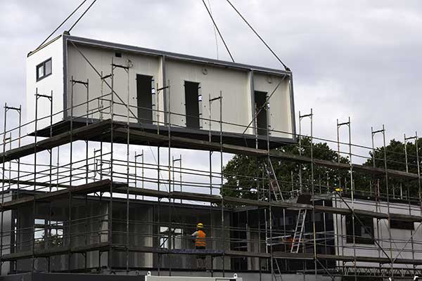 Modulbauteil wird von einem Kran auf ein Haus gehoben.