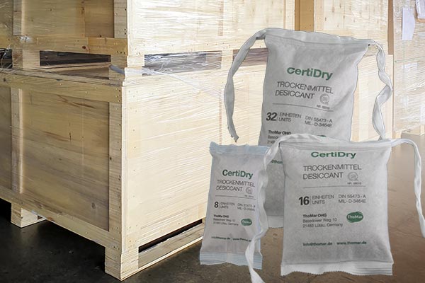 Several bags of the DIN desiccant CertiDry in front of wooden export boxes