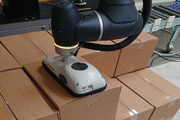 Cobot arm places a box on a pallet.